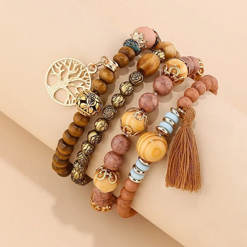 A blend of earthy textures and bohemian charm, Oakveil Bracelet brings together natural wooden beads, soft stone tones, tassel details, and the symbolic Tree of Life charm. Its layered design creates a free-spirited look that feels warm, artistic, and timeless.