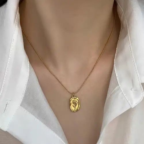 Like a timeless rose preserved within a golden keepsake, this elegant necklace captures a beautiful sense of romance, grace, and vintage charm. Featuring a sculpted rose motif set within an organic oval medallion, it creates a refined statement that feels delicate, meaningful, and effortlessly luxurious.