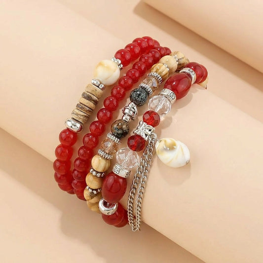 A warm blend of earthy textures and rustic elegance, this layered bracelet brings together rich crimson beads, natural wooden accents, crystal details, and soft shell charms. Its handcrafted boho spirit creates a free-spirited look filled with warmth and character.