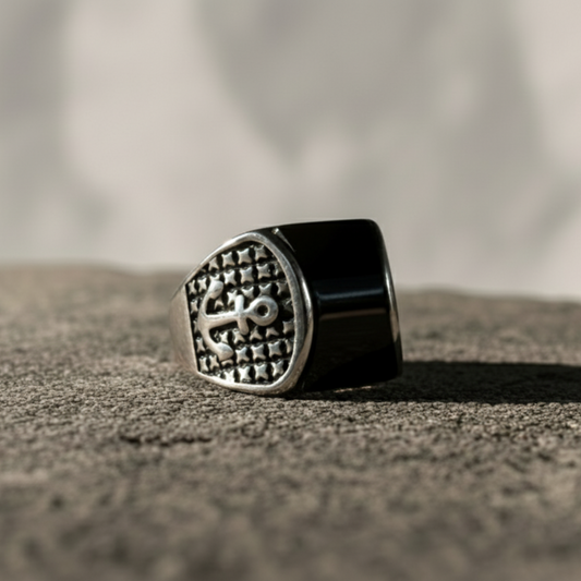 A bold men’s signet ring inspired by the unwavering power of the anchor and the mystery of the abyss. Crafted in antiqued silver and crowned with a deep black onyx face, this ring reflects resilience, loyalty, and quiet dominance. The engraved anchor emblem adds a nautical edge, making it a statement of grounding strength and timeless masculinity.