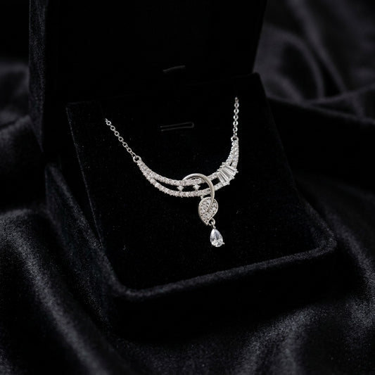 A flowing curve of shimmering crystals paired with a delicate heart drop, this necklace captures an elegant sparkle that feels graceful from every angle. The soft cascading design adds a refined charm that beautifully balances romance and modern luxury.