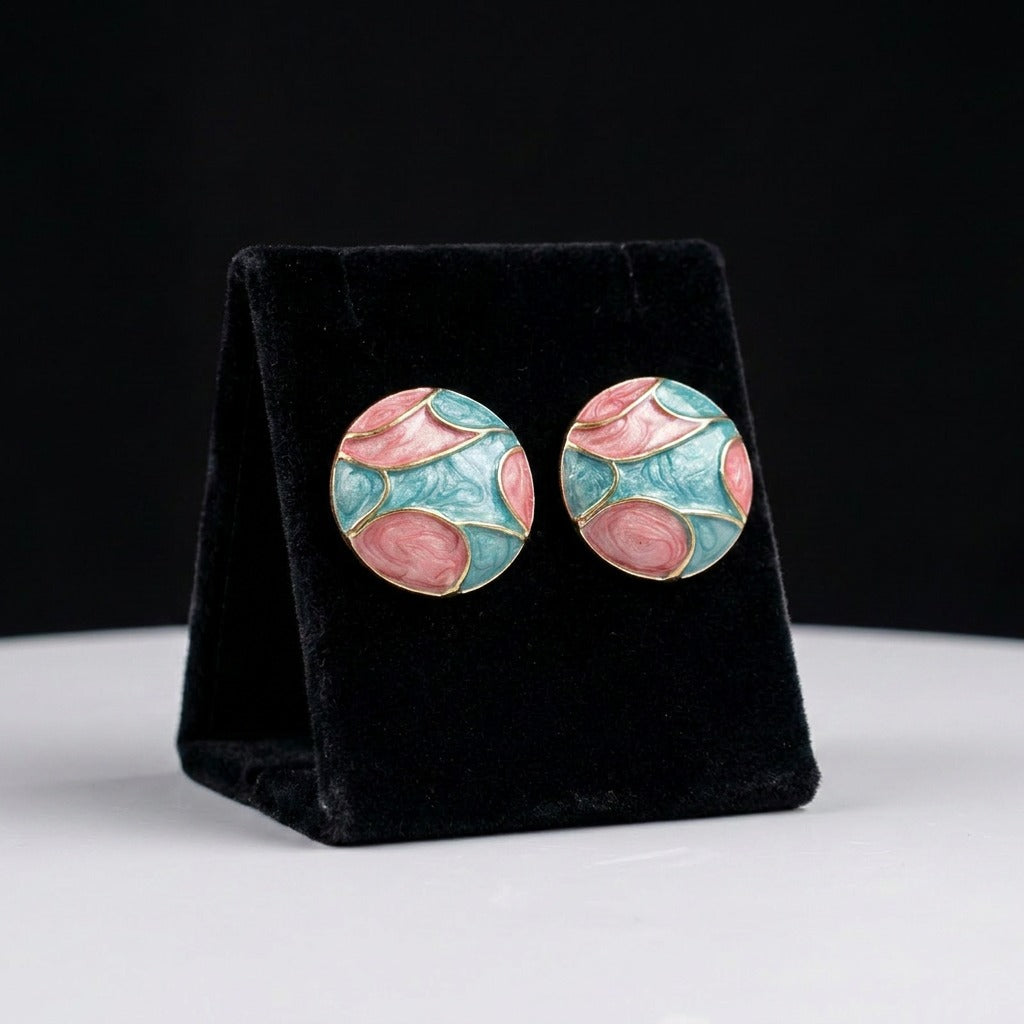 A dreamy fusion of blooming petals and ocean tides, these earrings showcase flowing blush pink and aqua enamel patterns that resemble watercolor waves meeting delicate florals. Their artistic palette creates a soft statement full of charm and elegance.