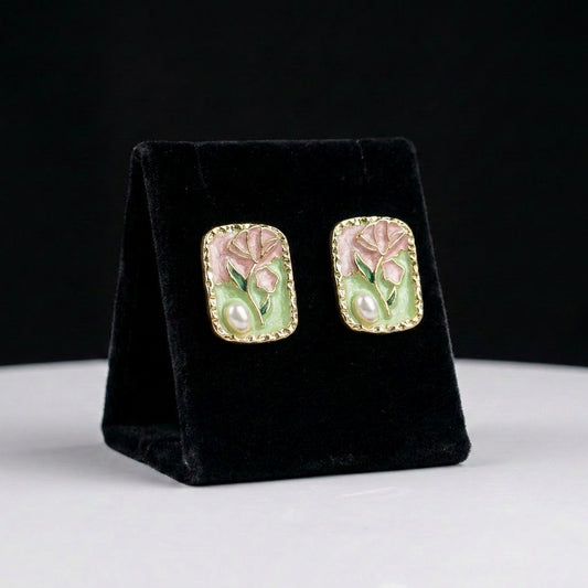 A soft floral painting brought to life, these earrings blend blush pink petals, sage green enamel, and a delicate pearl accent within an elegant framed silhouette. Their artistic charm feels vintage, graceful, and beautifully romantic.