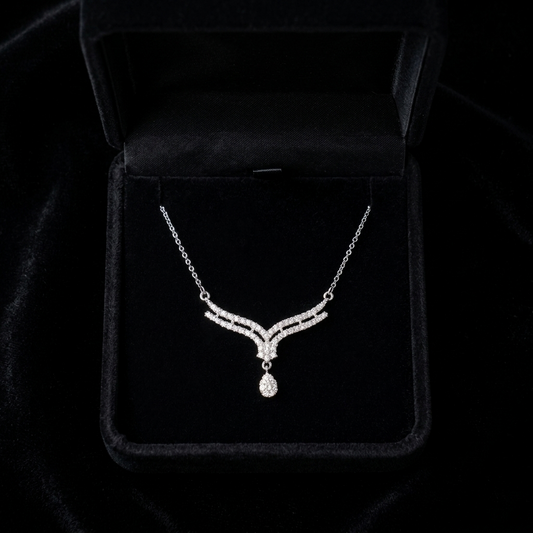 A soft cascade of shimmering curves and delicate brilliance, this necklace captures an elegant flowing silhouette that feels effortlessly graceful. The layered crystal lines and suspended teardrop detail create a refined sparkle designed to elevate every look.