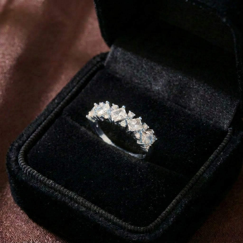 A graceful blend of royal elegance and delicate brilliance, this ring features a row of sparkling square-cut stones framed with intricate lace-like accents. Its refined silhouette creates a crown-inspired charm that feels luxurious, feminine, and timeless.