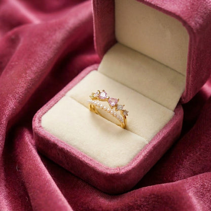 Like a tiny bow resting on a royal crown, this charming ring captures a playful blend of sweetness, elegance, and soft feminine sparkle. Featuring delicate bow-shaped crystal accents paired with a graceful pearl-lined curve, it creates a dreamy statement that feels cute, graceful, and effortlessly luxurious.