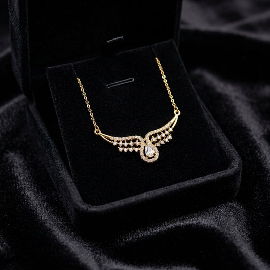 A graceful curve of shimmering crystals flowing into a radiant teardrop centerpiece, this necklace captures an elegant sparkle that feels delicate yet striking. The wing-like silhouette and soft crystal shine create a timeless look perfect for both festive styling and everyday elegance.