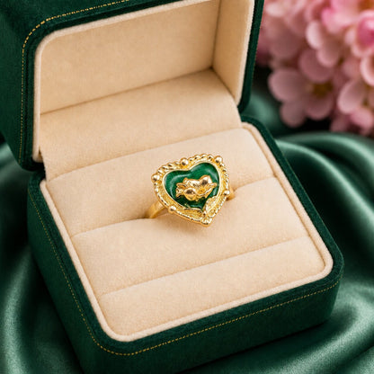 Like a secret flower blooming inside an enchanted heart, this elegant ring captures a magical blend of romance, nature, and vintage-inspired charm. Featuring a rich enamel heart centerpiece with a sculpted golden floral motif, it creates a distinctive statement that feels artistic, feminine, and effortlessly luxurious.