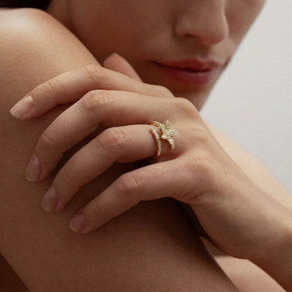 A radiant bloom captured in delicate brilliance, this ring features a sparkling floral silhouette paired with a graceful split pavé band. Its petal-inspired design creates a soft luminous charm that feels elegant, feminine, and enchanting.