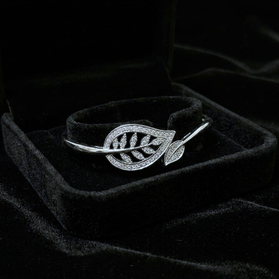 A graceful flow of nature captured in a delicate form, this vine-inspired bracelet wraps around the wrist with effortless elegance. The shimmering leaf details and soft curved silhouette create a look that feels both refined and naturally radiant.