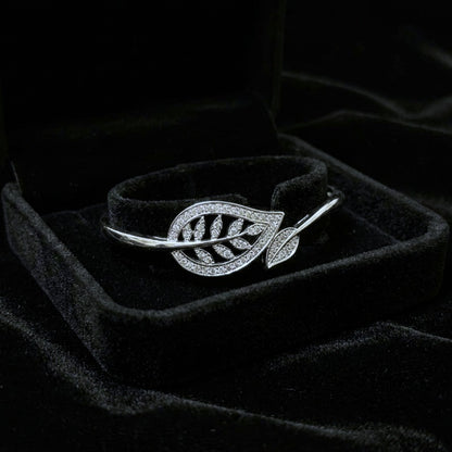 A graceful flow of nature captured in a delicate form, this vine-inspired bracelet wraps around the wrist with effortless elegance. The shimmering leaf details and soft curved silhouette create a look that feels both refined and naturally radiant.
