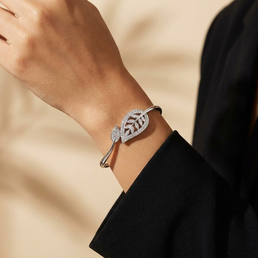 A graceful flow of nature captured in a delicate form, this vine-inspired bracelet wraps around the wrist with effortless elegance. The shimmering leaf details and soft curved silhouette create a look that feels both refined and naturally radiant.
