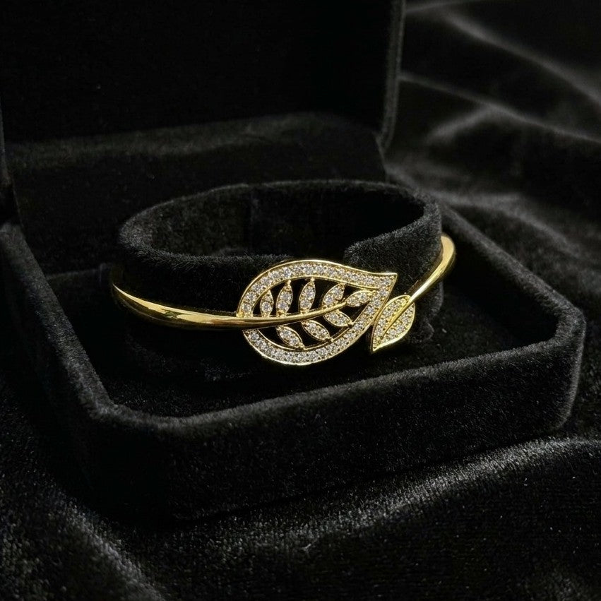 A graceful flow of nature captured in a delicate form, this vine-inspired bracelet wraps around the wrist with effortless elegance. The shimmering leaf details and soft curved silhouette create a look that feels both refined and naturally radiant.