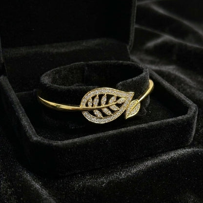 A graceful flow of nature captured in a delicate form, this vine-inspired bracelet wraps around the wrist with effortless elegance. The shimmering leaf details and soft curved silhouette create a look that feels both refined and naturally radiant.