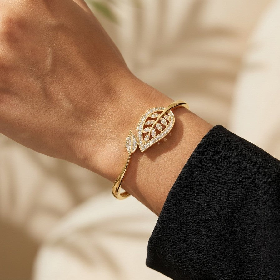 A graceful flow of nature captured in a delicate form, this vine-inspired bracelet wraps around the wrist with effortless elegance. The shimmering leaf details and soft curved silhouette create a look that feels both refined and naturally radiant.