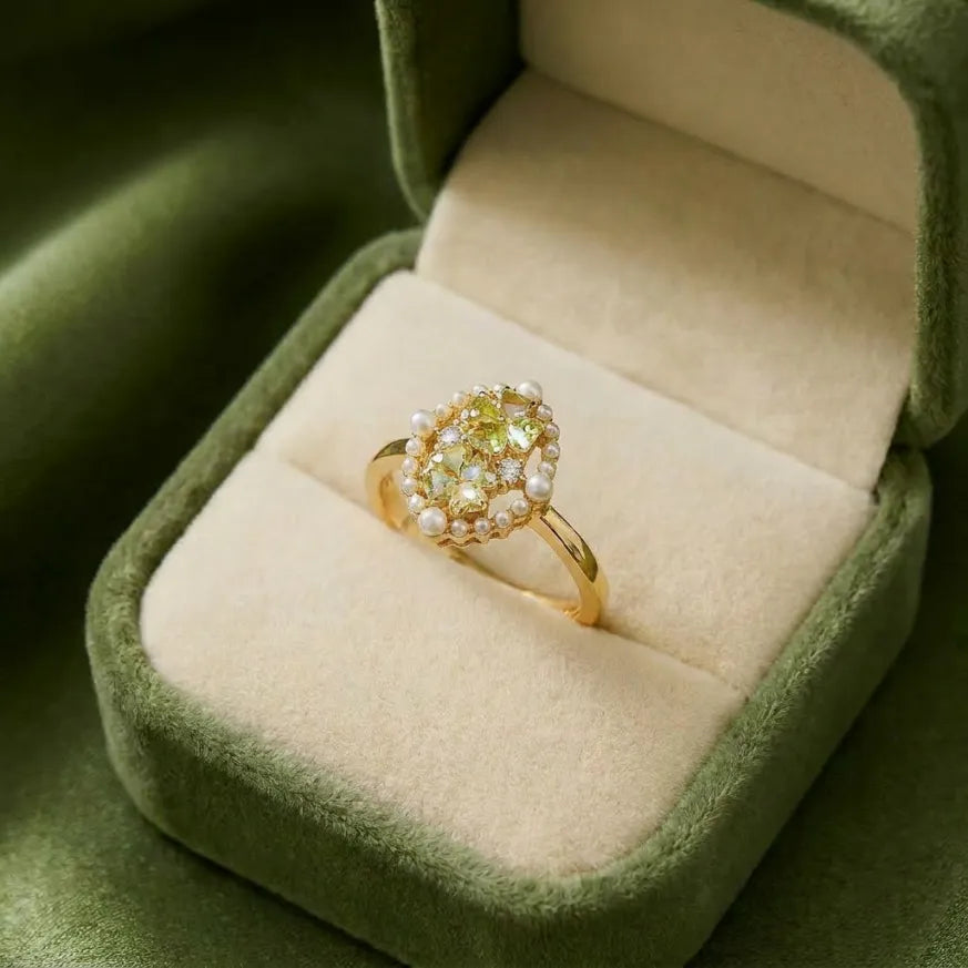 A radiant bloom of pearls and sparkling crystals, this ring captures the beauty of a sunlit garden in full bloom. Framed with delicate pearl accents and adorned with shimmering green-toned stones, it creates a graceful statement that feels fresh, enchanting, and effortlessly elegant. 