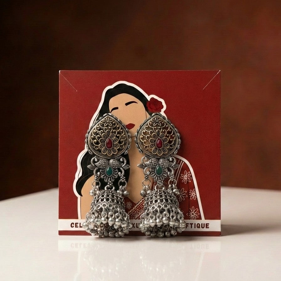 A rich blend of tradition and regal charm, this piece captures the beauty of intricate craftsmanship with vibrant red and green accents, The detailed floral top and layered jhumka dome create a striking presence that feels both festive and timeless