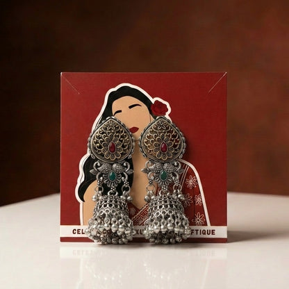 A rich blend of tradition and regal charm, this piece captures the beauty of intricate craftsmanship with vibrant red and green accents, The detailed floral top and layered jhumka dome create a striking presence that feels both festive and timeless