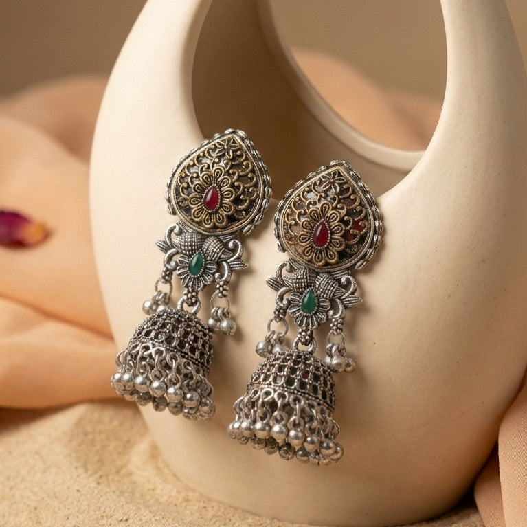 A rich blend of tradition and regal charm, this piece captures the beauty of intricate craftsmanship with vibrant red and green accents, The detailed floral top and layered jhumka dome create a striking presence that feels both festive and timeless