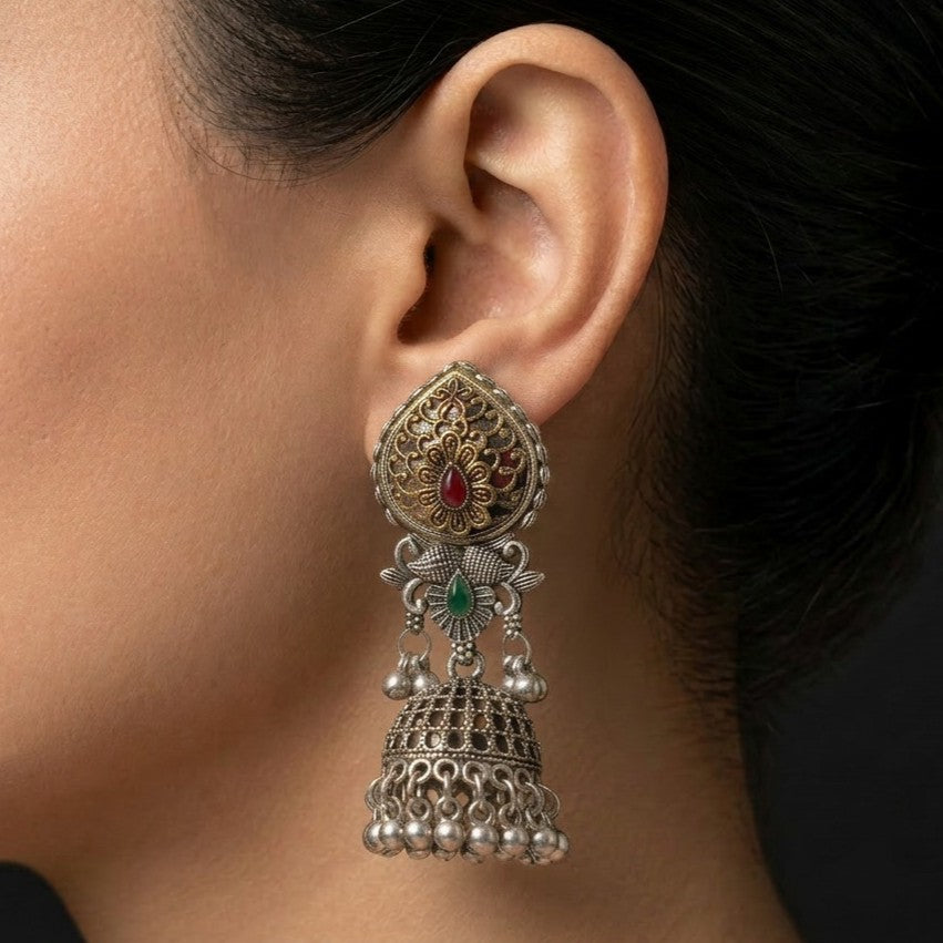 A rich blend of tradition and regal charm, this piece captures the beauty of intricate craftsmanship with vibrant red and green accents, The detailed floral top and layered jhumka dome create a striking presence that feels both festive and timeless