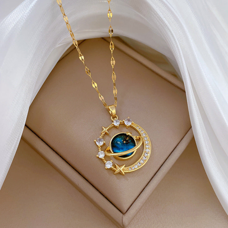 The Infinity Galaxy Necklace, a celestial masterpiece designed to capture the magic of the cosmos. Featuring a luminous deep blue planet orbited by shimmering cubic zirconia stars, this pendant is beautifully framed in a radiant gold-tone setting, perfect for dreamers, stargazers, and lovers of unique jewelry.