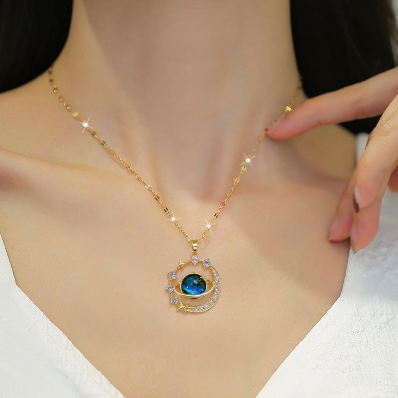 The Infinity Galaxy Necklace, a celestial masterpiece designed to capture the magic of the cosmos. Featuring a luminous deep blue planet orbited by shimmering cubic zirconia stars, this pendant is beautifully framed in a radiant gold-tone setting, perfect for dreamers, stargazers, and lovers of unique jewelry.