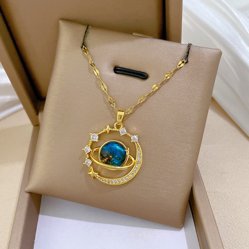 The Infinity Galaxy Necklace, a celestial masterpiece designed to capture the magic of the cosmos. Featuring a luminous deep blue planet orbited by shimmering cubic zirconia stars, this pendant is beautifully framed in a radiant gold-tone setting, perfect for dreamers, stargazers, and lovers of unique jewelry.