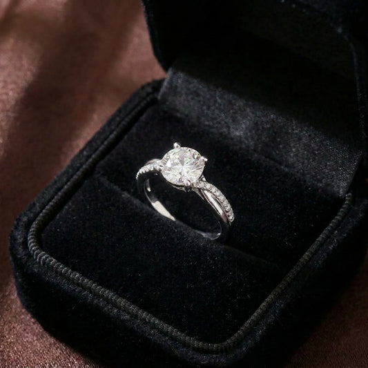 A graceful brilliance wrapped in timeless elegance, this ring features a radiant round-cut centerpiece embraced by a delicately curved pavé band. Its soft sparkle and refined silhouette create a look that feels romantic, luxurious, and effortlessly classic.