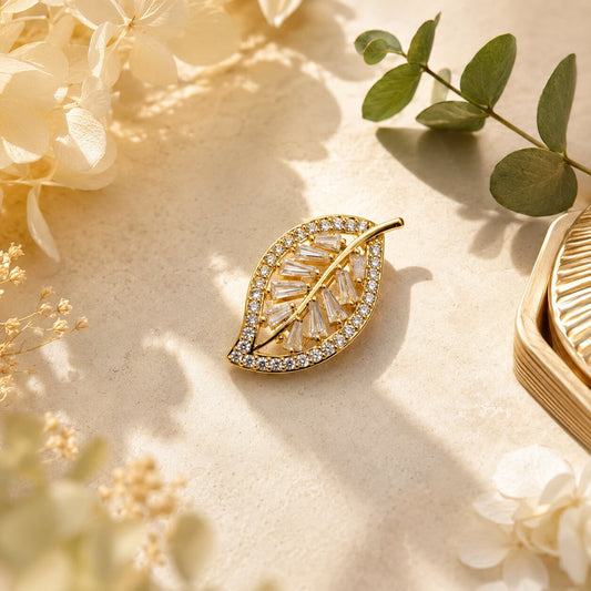 Like a golden leaf illuminated by the softest morning light, this elegant brooch captures a beautiful sense of growth, grace, and natural radiance. Featuring a delicate leaf silhouette filled with sparkling crystal accents and refined baguette-cut stones, it creates a luminous statement that feels graceful, sophisticated, and effortlessly luxurious.
