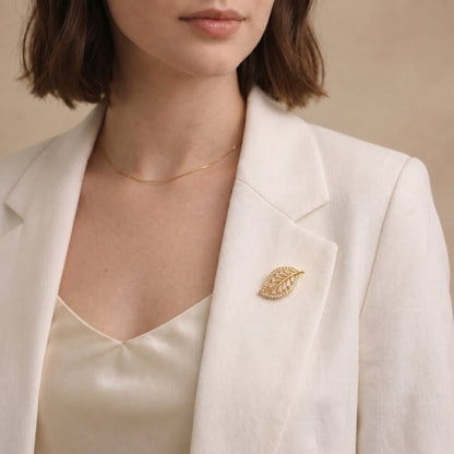 Like a golden leaf illuminated by the softest morning light, this elegant brooch captures a beautiful sense of growth, grace, and natural radiance. Featuring a delicate leaf silhouette filled with sparkling crystal accents and refined baguette-cut stones, it creates a luminous statement that feels graceful, sophisticated, and effortlessly luxurious.