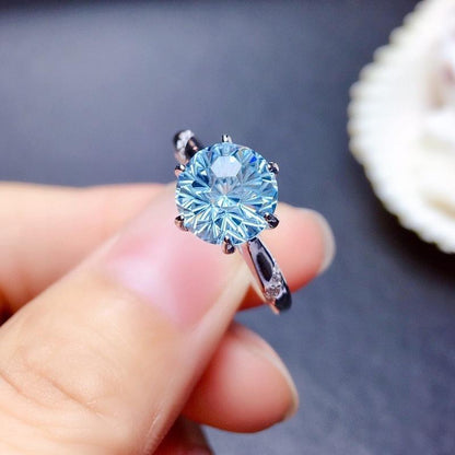Lunara Ice Ring features a mesmerizing round sea-blue firework-cut stone that catches light from every angle. Set on a sleek silver-tone band, this ring delivers statement sparkle while remaining soft, feminine, and wearable for everyday moments.