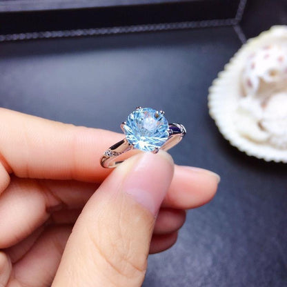Lunara Ice Ring features a mesmerizing round sea-blue firework-cut stone that catches light from every angle. Set on a sleek silver-tone band, this ring delivers statement sparkle while remaining soft, feminine, and wearable for everyday moments.