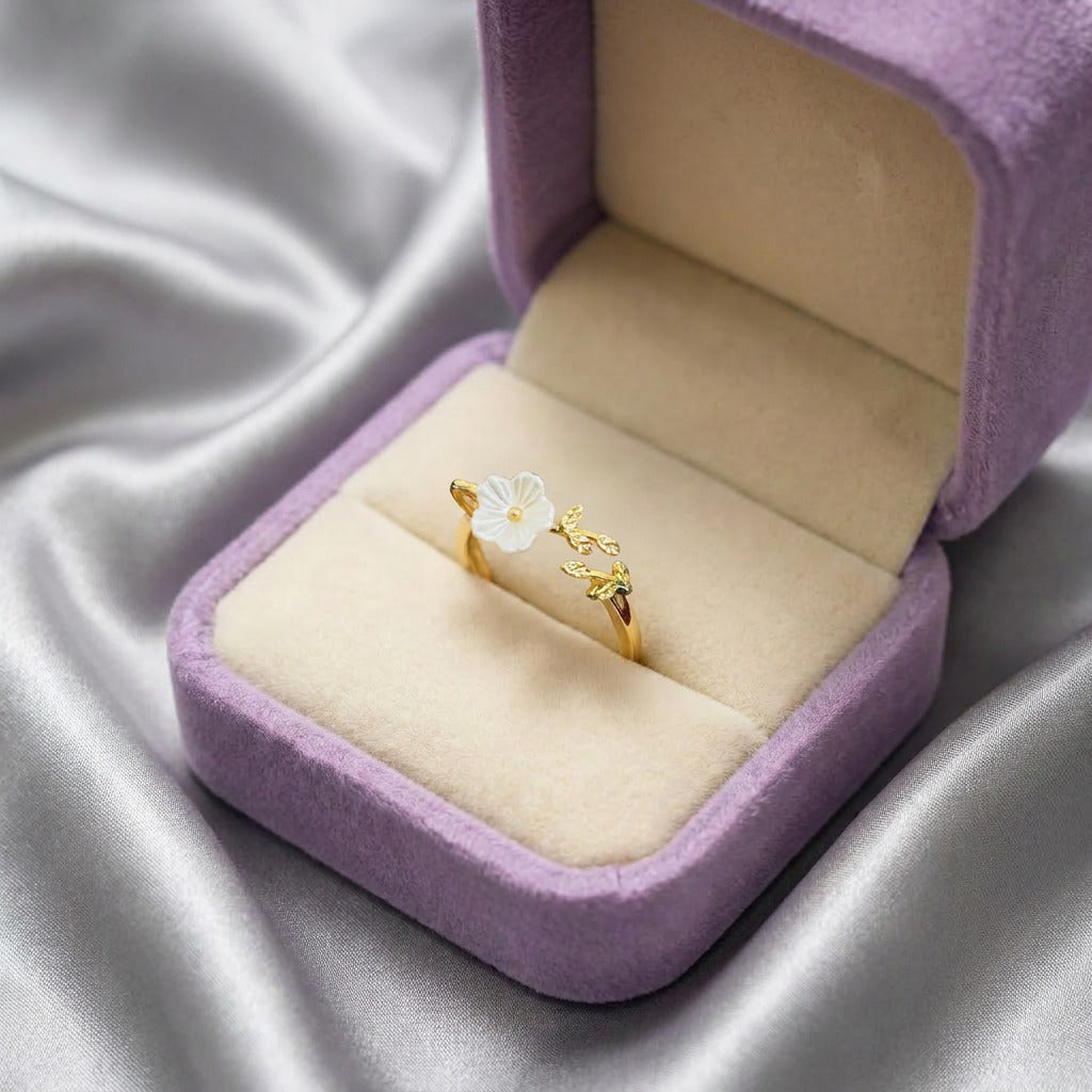A graceful bloom captured in gold, the Meadowbloom Ring features a delicate white flower paired with a sparkling leafy vine. Inspired by wildflowers swaying through a sunlit meadow, this charming design brings a touch of nature's elegance to every look.