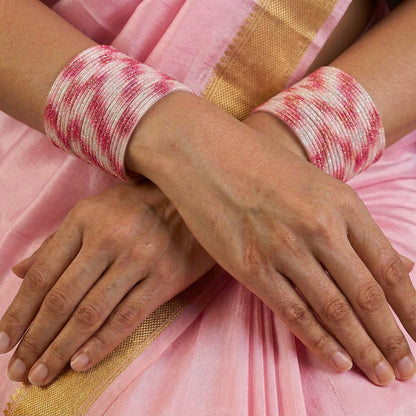 A radiant blend of tradition and celebration, these bangles glow in a vibrant pink hue adorned with delicate golden accents that shimmer beautifully in the light. Their festive sparkle and graceful stacked look bring a joyful charm to every ethnic moment.