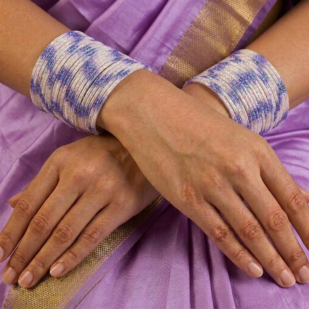 A radiant blend of tradition and celebration, these bangles glow in a vibrant pink hue adorned with delicate golden accents that shimmer beautifully in the light. Their festive sparkle and graceful stacked look bring a joyful charm to every ethnic moment.