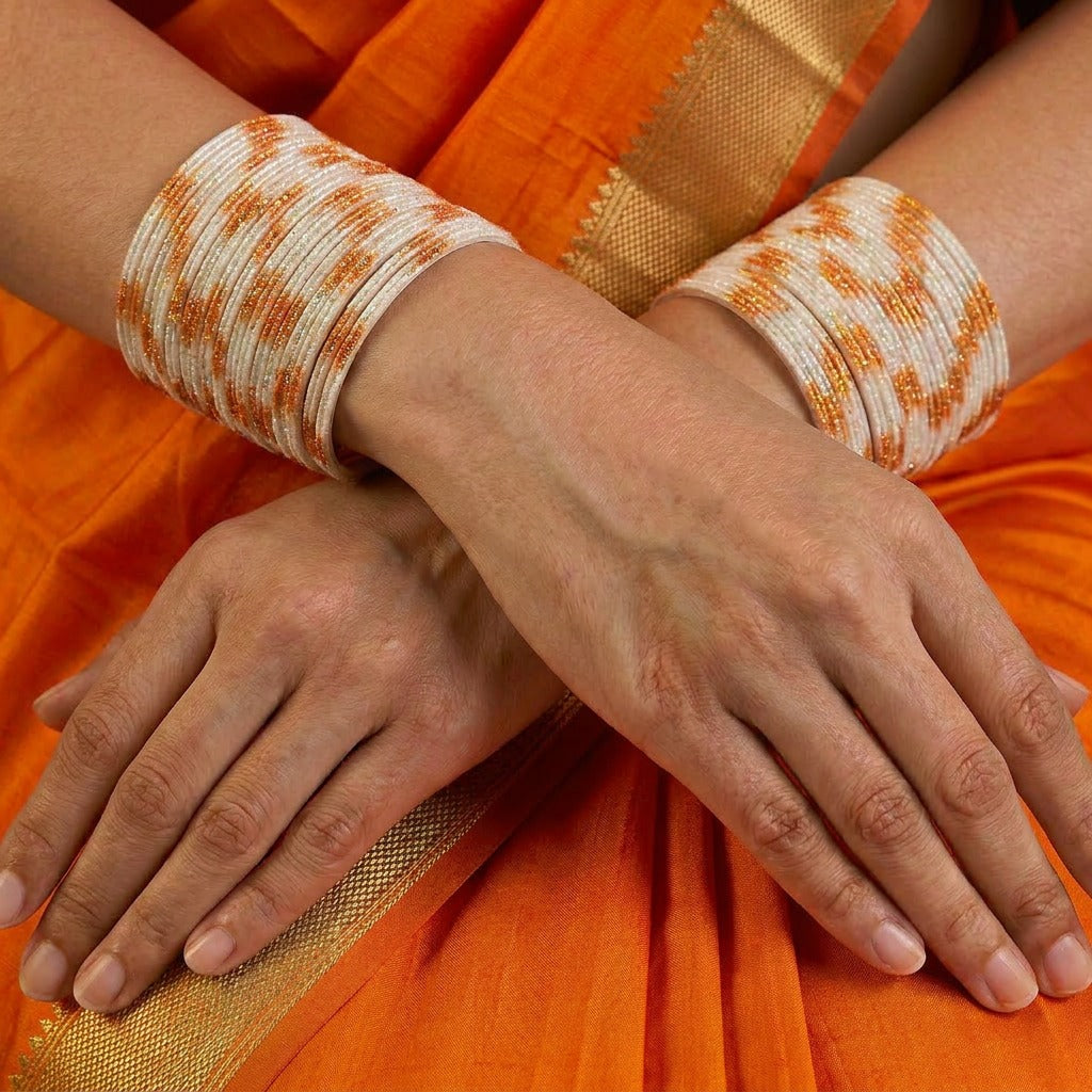 A radiant blend of tradition and celebration, these bangles glow in a vibrant pink hue adorned with delicate golden accents that shimmer beautifully in the light. Their festive sparkle and graceful stacked look bring a joyful charm to every ethnic moment.