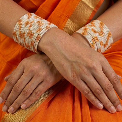 A radiant blend of tradition and celebration, these bangles glow in a vibrant pink hue adorned with delicate golden accents that shimmer beautifully in the light. Their festive sparkle and graceful stacked look bring a joyful charm to every ethnic moment.