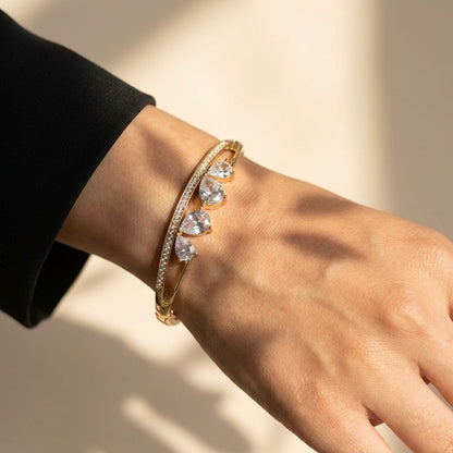 A sleek brilliance that flows with effortless grace, this bracelet captures the beauty of cascading light in a refined, modern form. The line of shimmering crystals paired with delicate drop accents creates a soft, radiant movement that feels both luxurious and timeless.