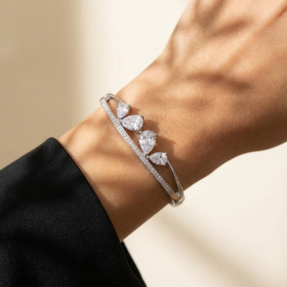 A sleek brilliance that flows with effortless grace, this bracelet captures the beauty of cascading light in a refined, modern form. The line of shimmering crystals paired with delicate drop accents creates a soft, radiant movement that feels both luxurious and timeless.