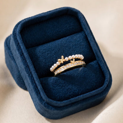 Like tiny butterflies dancing along a trail of glowing pearls, this elegant ring captures a graceful blend of softness, sparkle, and feminine charm. Featuring a delicate pearl-lined curve paired with shimmering crystal accents and golden butterfly motifs, it creates a refined statement that feels dreamy, enchanting, and effortlessly luxurious.