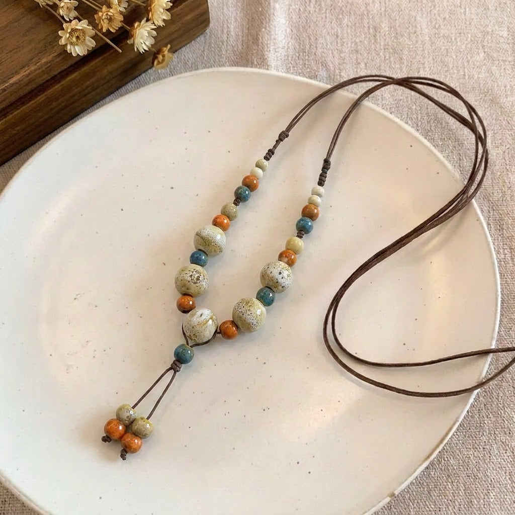 Inspired by sunlit river stones and the quiet beauty of nature, this necklace features earthy ceramic-style beads arranged in a harmonious blend of warm and calming tones. Its handcrafted look and organic textures create a relaxed bohemian charm that feels timeless, artistic, and effortlessly wearable.