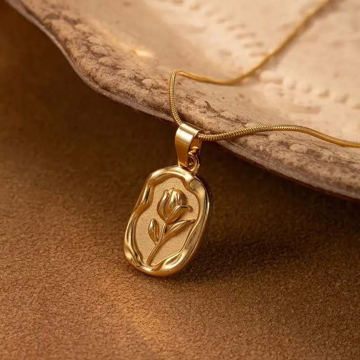 Like a timeless rose preserved within a golden keepsake, this elegant necklace captures a beautiful sense of romance, grace, and vintage charm. Featuring a sculpted rose motif set within an organic oval medallion, it creates a refined statement that feels delicate, meaningful, and effortlessly luxurious.