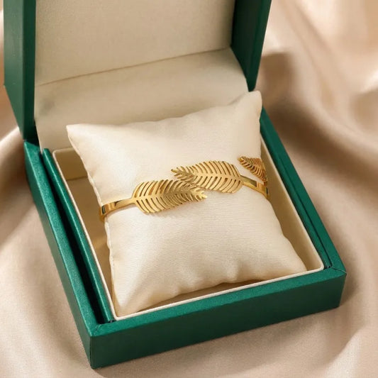 Inspired by sunlit palms swaying in a warm breeze, this cuff features an elegant overlapping leaf design crafted in a polished gold-tone finish. Its open silhouette and nature-inspired detailing create a statement that feels graceful, modern, and effortlessly sophisticated.
