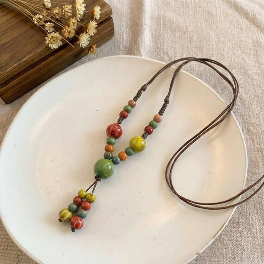 A cheerful blend of sunlit colors and handcrafted charm, this necklace features vibrant ceramic-style beads arranged on a natural cord for a playful boho look. Its bright red, green, yellow, and blue tones create a joyful statement that feels artistic, earthy, and effortlessly unique.
