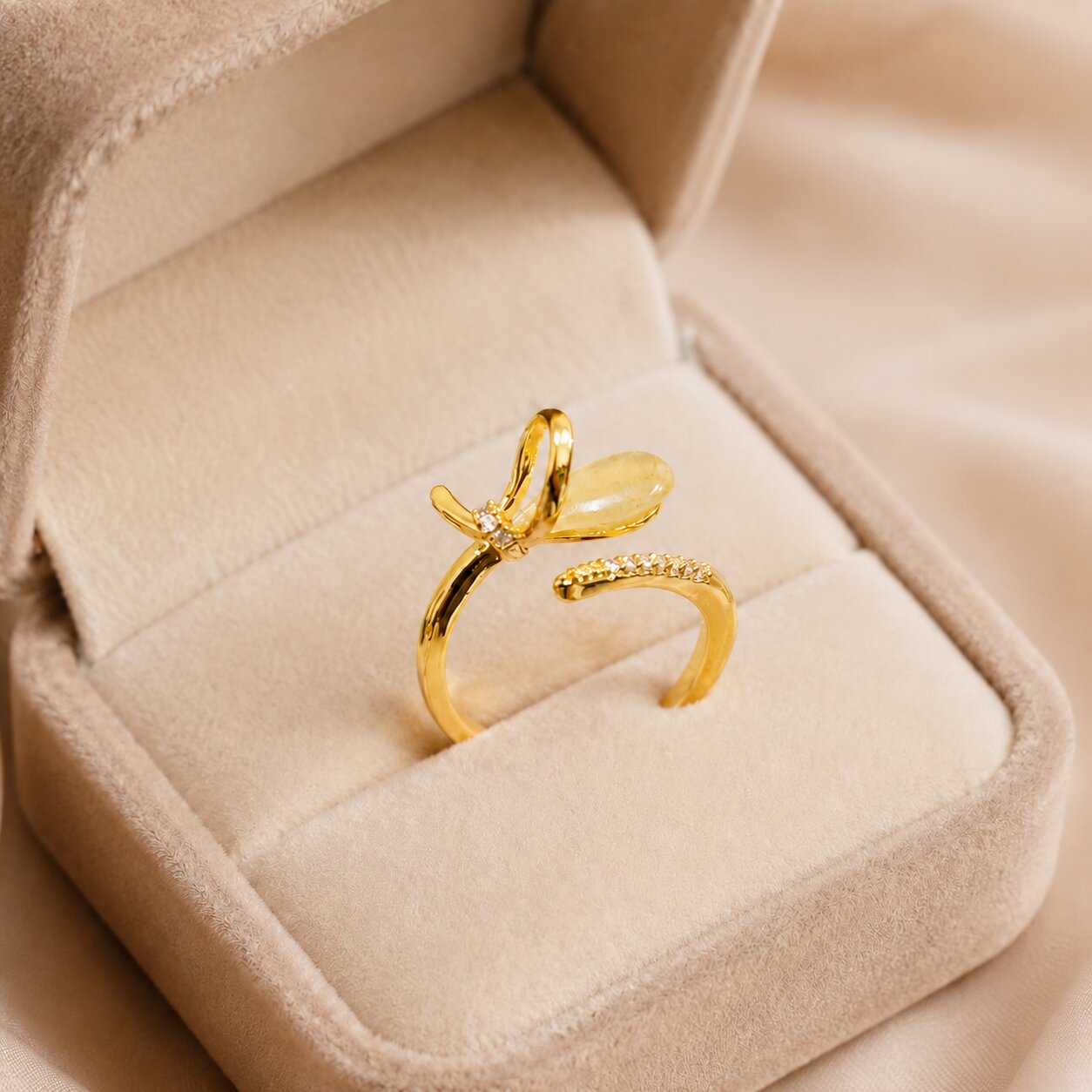 A golden flutter of light and grace, this ring features a delicate wing-inspired design with a soft translucent accent and shimmering crystal details. Its open silhouette creates an airy, elegant charm that feels fresh, feminine, and beautifully unique.