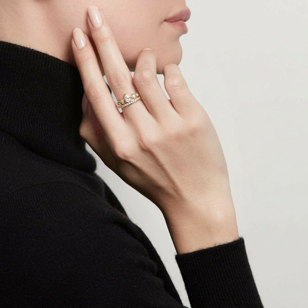 A graceful crown-inspired silhouette adorned with shimmering stones, Tiarabelle Ring captures the elegance of a tiny royal tiara wrapped around your finger. The pear-cut center crystal and sparkling accents create a look that feels delicate, regal, and timeless.