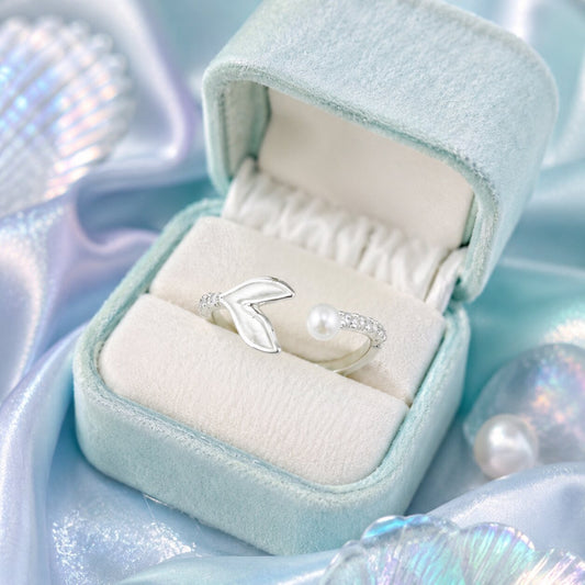 A graceful meeting of ocean tides and timeless elegance, this ring features a delicate pearl paired with a flowing whale-tail-inspired silhouette. Its airy open design and shimmering accents create a soft coastal charm that feels serene, feminine, and effortlessly unique.
