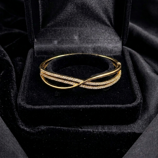 A graceful twist of golden curves and delicate shimmer, this cuff captures the beauty of fluid elegance in a sleek modern silhouette. Its intertwined design creates a soft sparkling flow that feels effortlessly refined and timeless.