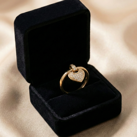 A romantic statement ring defined by a delicate hanging heart silhouette, softly paved with shimmering zircon stones. The Velmora Heart Ring is designed to capture love in motion graceful, expressive, and full of feeling. Its suspended heart detail adds gentle movement, making the design feel alive, emotional, and irresistibly charming.