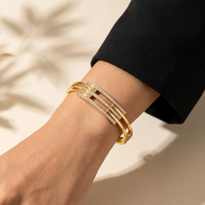 A refined play of clean lines and crystal brilliance, this cuff captures modern elegance in a sleek layered silhouette. The parallel crystal bars paired with a polished gold finish create a statement look that feels both bold and effortlessly sophisticated.